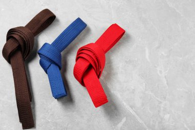 Gri mermer arka planda renkli karate kemerleri, düz yatış. Metin için boşluk