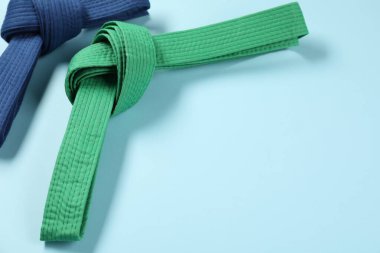 Açık mavi arkaplanda renkli karate kemerleri, metin için boşluk