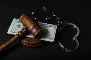 Law gavel, dollars and handcuffs on dark table clipart