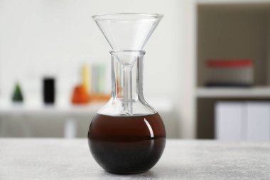 Kahverengi ham yağ ve açık gri masada filtre hunisi olan şişe.