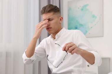 Evde acı çeken gözlüklü bunalmış bir adam.