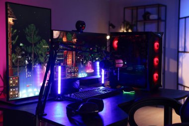 Video oyunları oynuyorum. Modern bilgisayar ve neon lambalı oyun koltuğu olan şık bir oda.