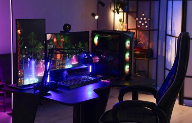 Video oyunları oynuyorum. Modern bilgisayar ve neon lambalı oyun koltuğu olan şık bir oda.