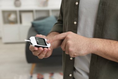 Diyabet testi. Evde glukometre kullanan adam, yakın plan.