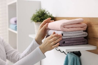 Kadın temiz havluları evin içinde diziyor, yakın plan.