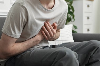 Evdeki kanepede kalbi yaralı bir adam, yakın plan.