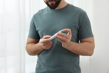 Diyabet testi. Kan şekeri seviyesini evde tükenmez kalemle ölçen bir adam var.