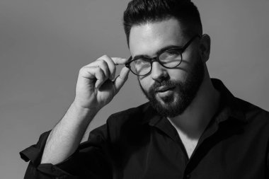 Gri arka planda sakallı yakışıklı bir adamın portresi. Siyah ve beyaz etkisi