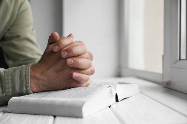 Din. Hıristiyan adam İncil için dua ediyor, beyaz ahşap masa, yakın çekim