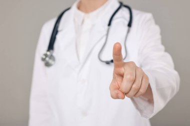 Gri arkaplanı gösteren steteskoplu bir doktor, yakın plan.