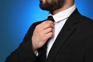 Takım elbiseli ve kravatlı iş adamı mavi arka planda, yakın plan.
