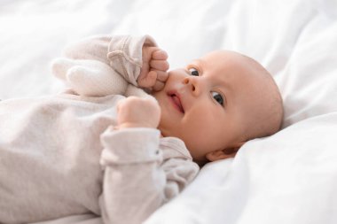 Beyaz çarşafların üzerinde uzanan tatlı bir bebek