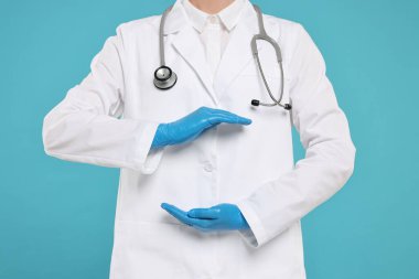 Steteskoplu doktor açık mavi arka planda bir şey tutuyor, yakın plan.