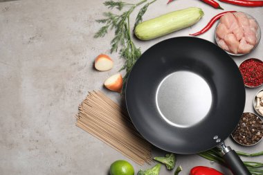 Gri masadaki ham malzemelerle çevrili boş demir tava, düz. Metin için boşluk
