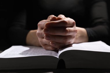 Din. Hıristiyan kadın masada İncil için dua ediyor, yakın plan.