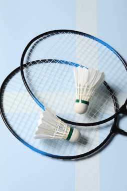 Tüy badminton mekik horozları ve açık mavi arka planda raketler