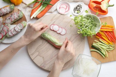 Beyaz ahşap masaya meyveli börek saran bir kadın.