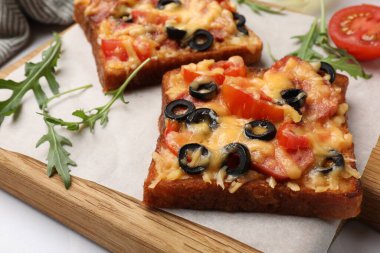 Lezzetli pizza tostları ve malzemeler beyaz masada, yakın plan.