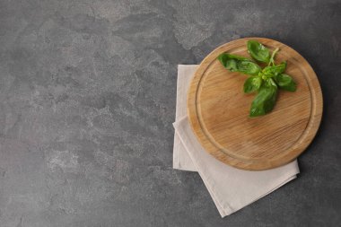 Tahta kesme tahtası, taze fesleğen ve gri masa peçetesi, üst manzara. Metin için boşluk