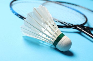 Tüy badminton mekik horozu ve açık mavi arka planda raketler, yakın plan