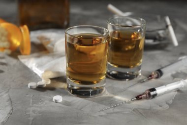 Alkol ve uyuşturucu bağımlılığı. Bardakta viski, şırınga, hap ve kokain gri masada, yakın plan.