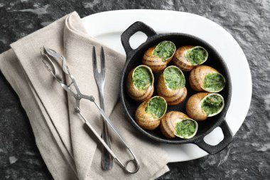 Gri desenli masada servis edilen pişirme kabında nefis pişmiş salyangozlar.