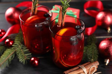 Kadehler, malzemeler ve siyah ahşap masa üzerindeki Noel dekoruyla Aromatik Sangria içeceği.