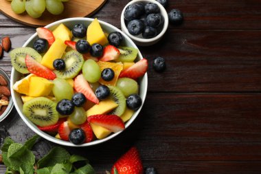 Lezzetli meyve salatası kasede ve ahşap masada malzemeler, düz yatak. Metin için boşluk