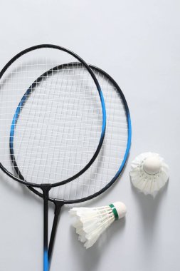 Kuş tüyü badminton mekikleri ve raketler gri arka planda, düz yatıyordu