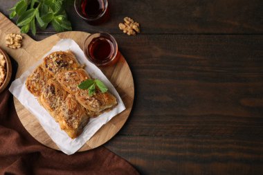 Doğu tatlıları. Lezzetli baklava parçaları, ahşap masada ceviz ve çay, düz yatak. Metin için boşluk