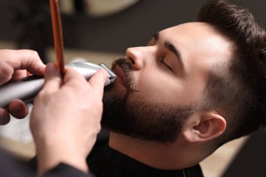 Berber dükkanında müşterinin bıyığını kesen profesyonel berber.