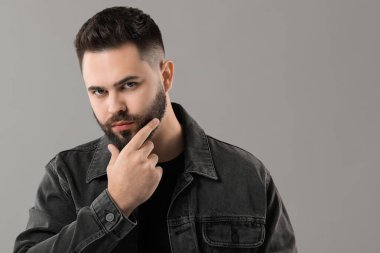 Gri arka planda bıyıklı genç adamın portresi