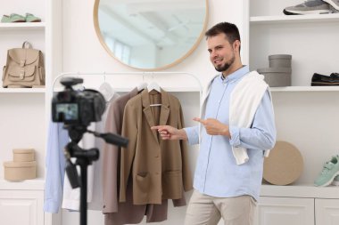 Gülümseyen moda blogcusu evde video kaydederken kıyafetlerini gösteriyor