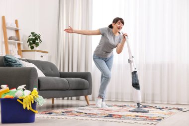 Mutlu genç ev hanımı evde temizlik yaparken eğleniyor.