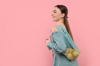 Pembe arka planda taze limon dolu bir torba kadın, mesaj için boşluk