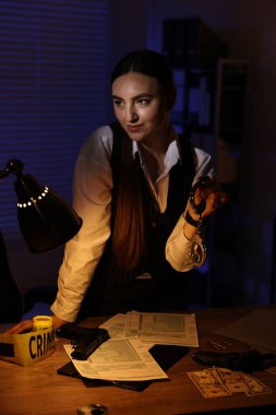 Geceleri ofiste elleri kelepçeli profesyonel bir dedektif.