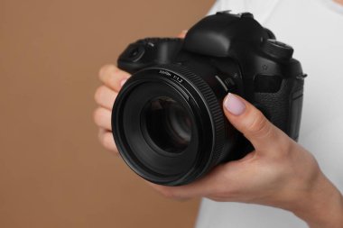 Kahverengi arka planda kamera olan fotoğrafçı, yakın plan