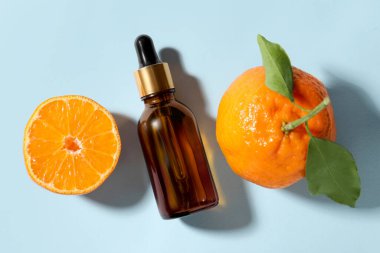 Aromatik mandalina yağı şişede ve turunçgiller açık mavi masada.