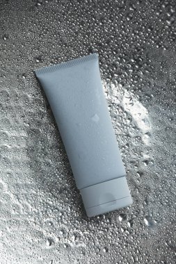 Gümüş zemin üzerinde nemlendirici krem, su damlaları, üst görünüm
