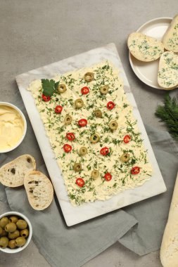 Taze tereyağı, dilimlenmiş zeytin, biber ve ekmek, gri masada, düz uzanış.