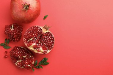 Taze nar ve yeşil yapraklar kırmızı arka planda, düz yerde. Metin için boşluk