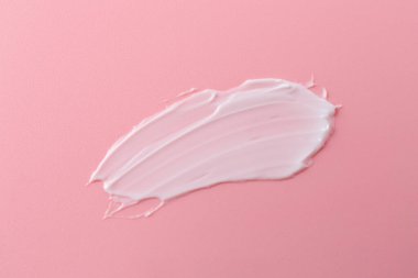 Pembe arka planda vücut bakım kremi örneği, üst görünüm.