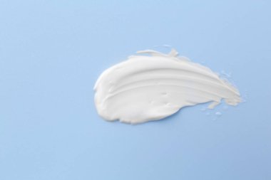 Açık mavi arka planda vücut bakım kremi örneği, üst görünüm