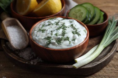Lezzetli yoğurt, yeşil soğan, salatalık, ahşap masada tuz ve limon, yakın plan.