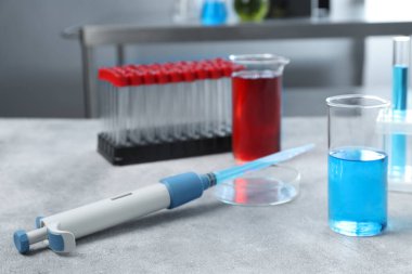 Laboratuvar analizi. Açık gri masada mikropipet, petri kabı, deney tüpleri ve test tüpleri.