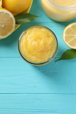 Kavanozda lezzetli limon ezmesi, taze narenciye meyvesi ve açık mavi ahşap masa üzerinde yeşil yapraklar. Metin için boşluk
