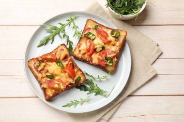 Lezzetli pizza tostları ve hafif ahşap masada taze roka.