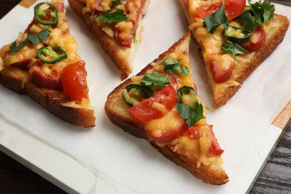 Tasty pizza toasts served on wooden table, closeup