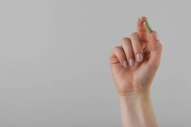 Gri arka planda vitamin kapsülü tutan kadın, metin için yeri olan yakın plan. Sağlık takviyesi