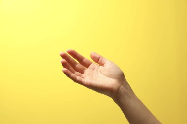 Sarı arka planda elinde bir şey tutan kadın, yakın plan.